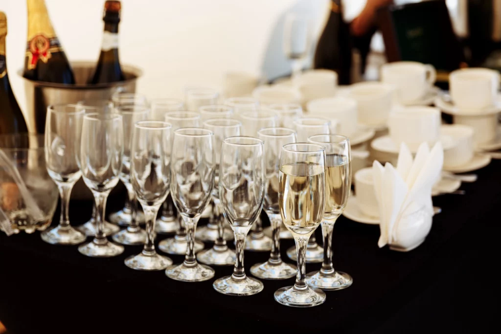 row glasses partially filled with champagne are lined up prepearing be served